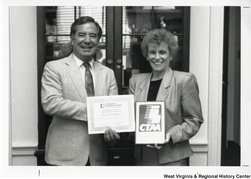 Congressman Nick Rahall II standing with an unidentified woman receiving an award from the Community Transportation Association of America (CTAA).