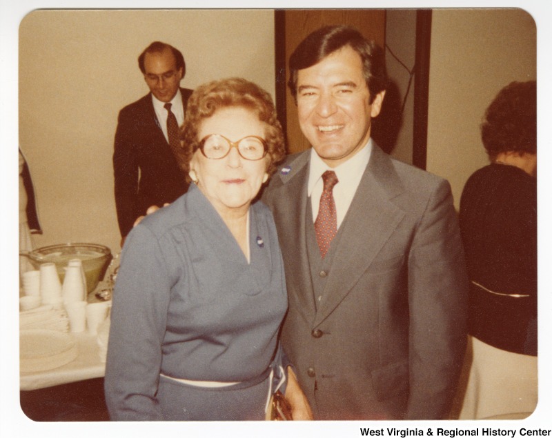 Congressman Nick Rahall, II and an unidentified woman at the Wildwood Senior Citizen's Home. The back of the photo has the following written on it: "Notice the "Chow Hound" in the back looking at the cookies."
