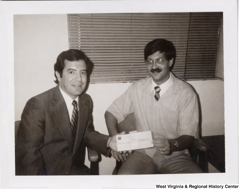 Congressman Nick Rahall, II and an unidentified man. Both are holding the ends of a check.