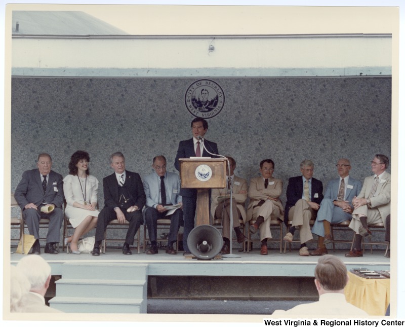 Congressman Nick Rahall, II (center) speaking at the groundbreaking of the Beckley sewage treatment plant. Senator Jennings Randolph sits to the far left on the stage and Senator Robert C. Byrd sits third from the left.