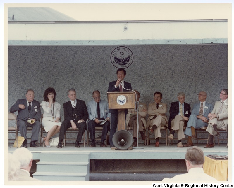 Congressman Nick Rahall, II (center) speaking at the groundbreaking of the Beckley sewage treatment plant. Senator Jennings Randolph sits to the far left on the stage and Senator Robert C. Byrd sits third from the left.