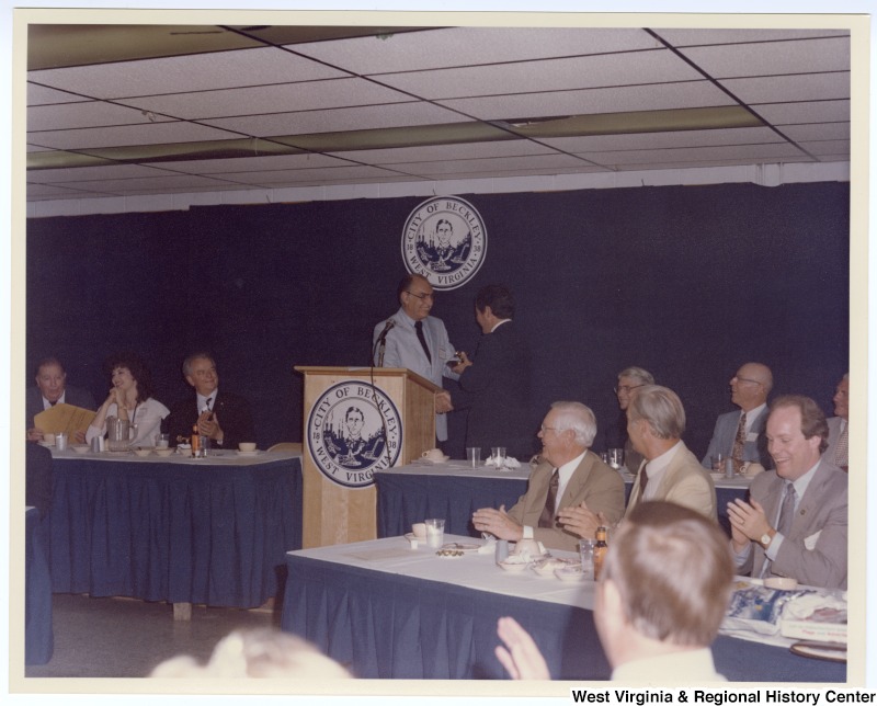 Senators Jennings Randolph (left in back row) and Robert C. Byrd (third from left in back row) as well as Congressman Nick Rahall, II (fourth from right in back row) at a banquet following the groundbreaking of the Beckley Sewage Treatment plant. Congressman Rahall is being thanked for his work on the project.