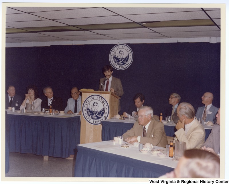 Senators Jennings Randolph (left in back row) and Robert C. Byrd (third from left in back row) as well as Congressman Nick Rahall, II (third from right in back row) at a banquet following the groundbreaking of the Beckley Sewage Treatment plant. An unknown man is speaking.