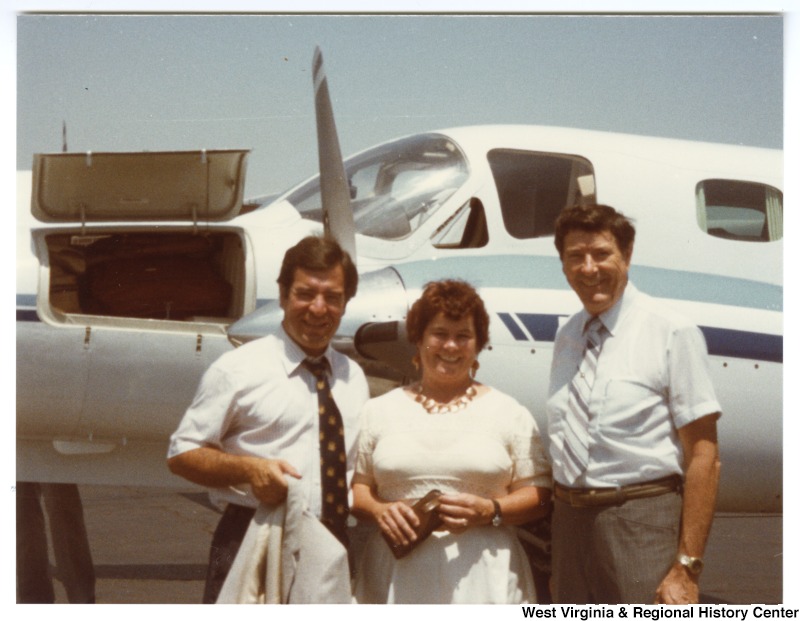 Congressman Nick Rahall, II (left) standing in front of a small airplane with an unidentified man and woman.