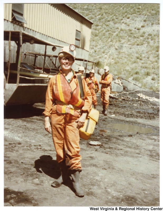 Unidentified woman in front of a group of unidentified people at the Rocky Mountain Energy Company.