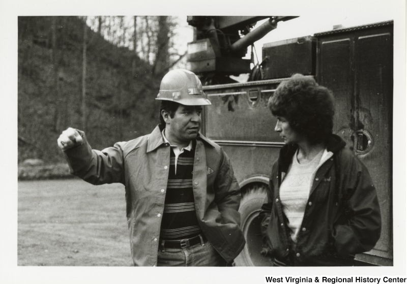 Photograph of Congressman Nick Rahall, II with an unidentified woman at the Hobet Coal Mine. They are standing in front of a work vehicle.