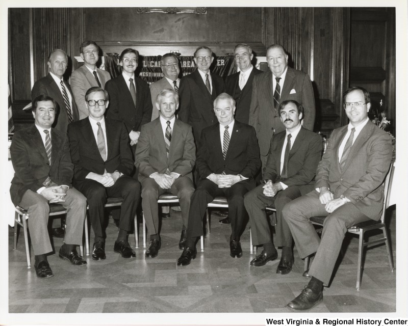 From left to right in the front row: Congressman Nick Rahall II, Senator John D. Rockefeller, West Virginia University (WVU) President Niel Bucklew, Senator Robert C. Byrd, Congressman Robert "Bob" Wise, and Congressman Harley O. Staggers. In the back row, Senator Jennings Randolph is on the far right in the back row. The other men in the back row are unidentified. Photo taken at WVU Alumni luncheon.