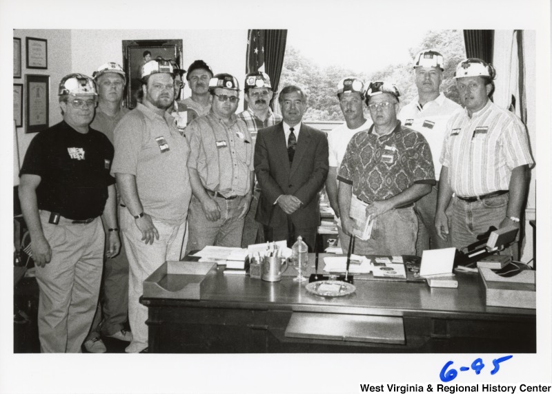 Congressman Nick Rahall, II (center in suit) in his office surrounded by a group of unidentified miners.