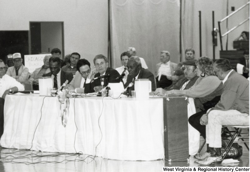 An unidentified group of people seated at a table on Marshall University's basketball court.