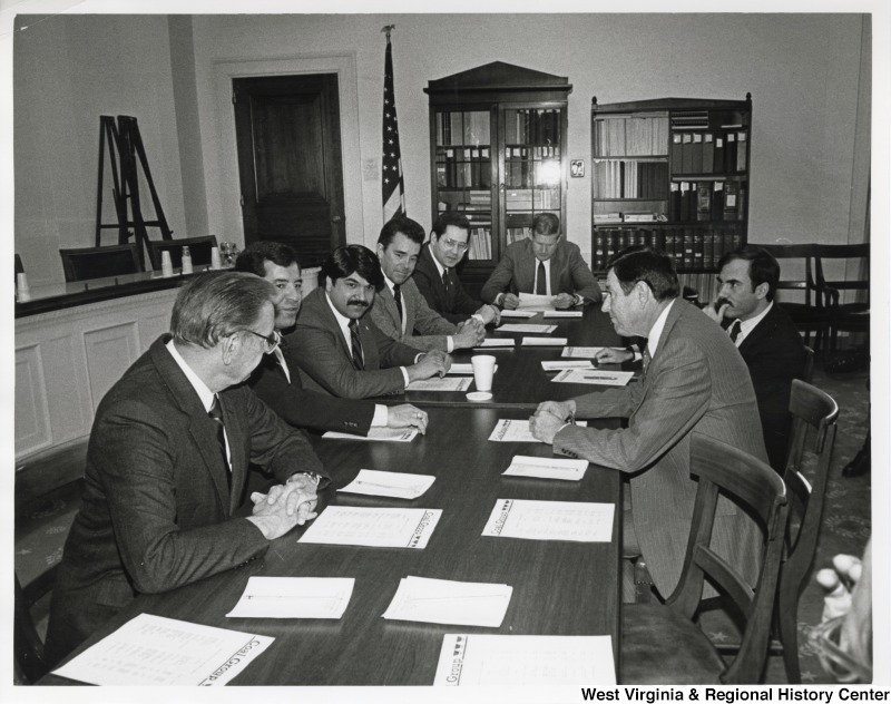 L-R around the table: Representative Tom Bevill (D-Ala); Representative Nick Rahall (D-W. Va.); Richard Trumka, president of the United Mine Workers of America (UMWA); Representative Doug Applegate (D-OH): Representative Alan Mollohan (D-W. Va.): Representative John Murtha (D-PA): an unidentified man,: and Representative Austin Murphy (D-PA). Representative Nick J. Rahall seated around a table with the seven men of the Congressional Coal Group.