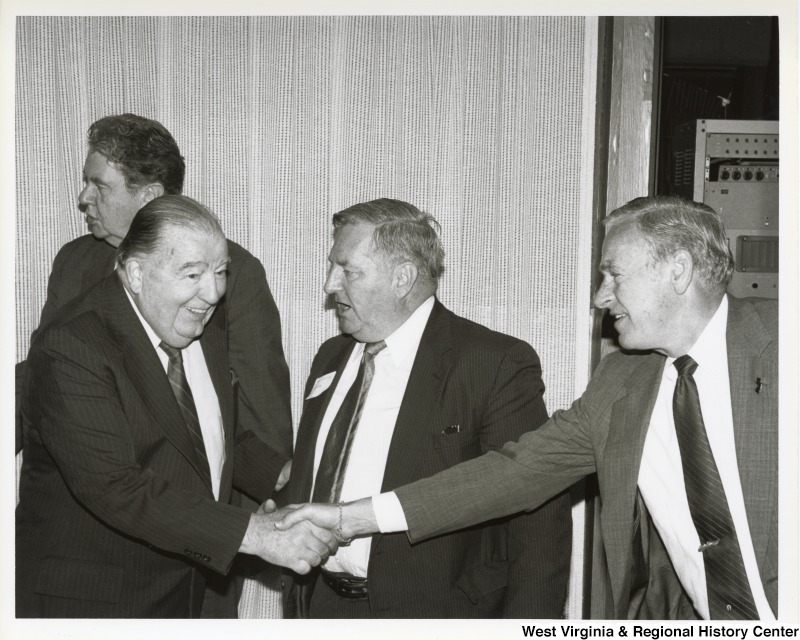 Senator Jennings Randolph (D-W.Va.) shakes hands with an unidentified man. Two other unidentified men are standing with them.