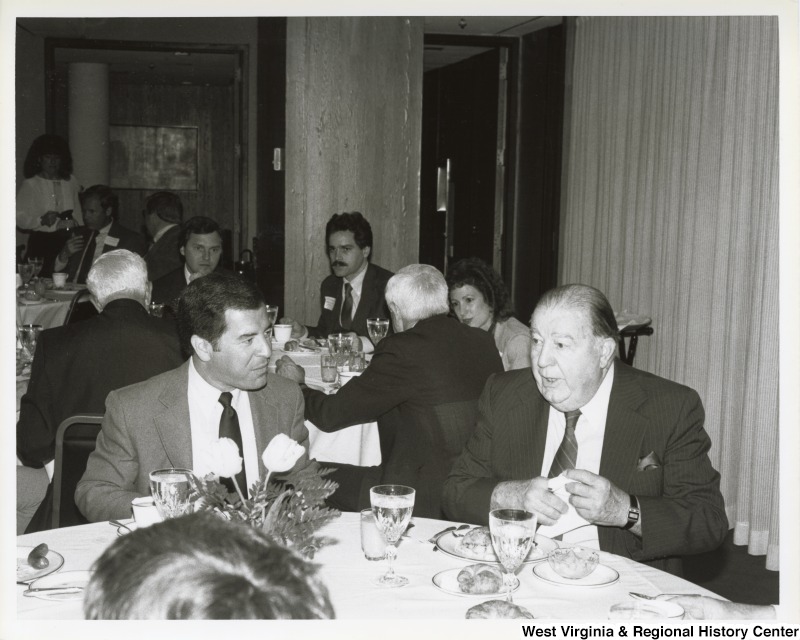 On the left, Representative Nick J. Rahall (D-W.Va) is seated and eating at a table with Senator Jennings Randolph (D-W.Va.).