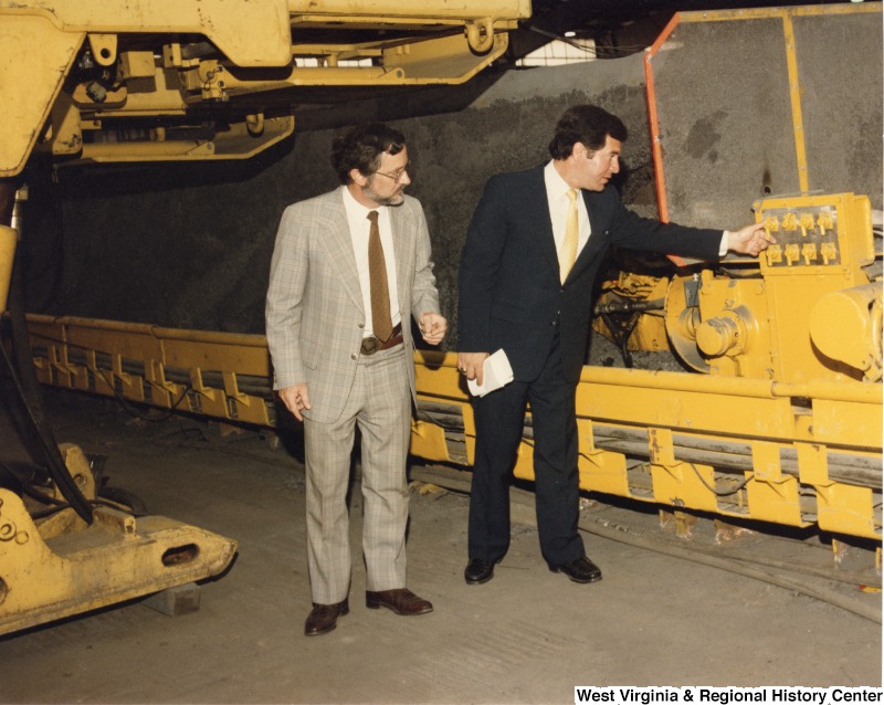 Representative Nick J. Rahall (D-W.Va.) touches switches on mining machinery beside an unidentified man.