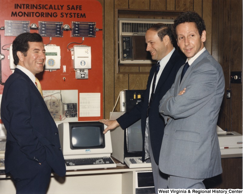 Representative Nick J. Rahall (D-W.Va.) talks to two unidentified men in front of a computer marked "Intrinsically Safe Monitoring System."
