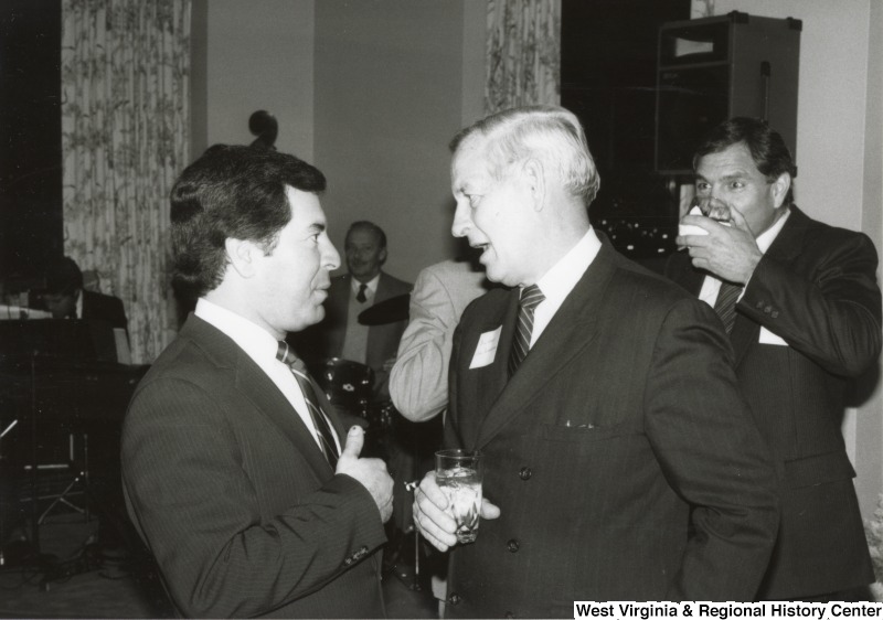 On the left, Representative Nick J. Rahall (D-W.Va.) talks with an unidentified man at an event.