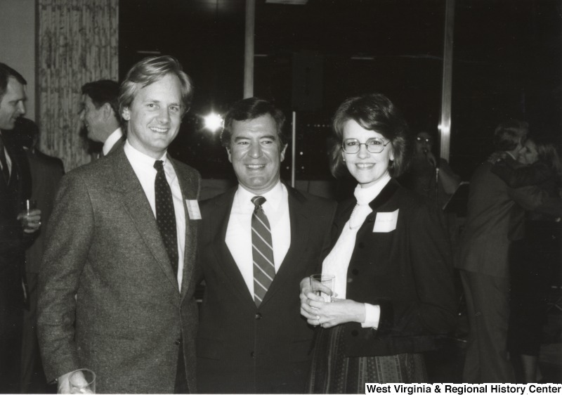 Representative Nick J. Rahall (D-W.Va.) stands between an unidentified man on the left and and unidentified woman on the right at an event.