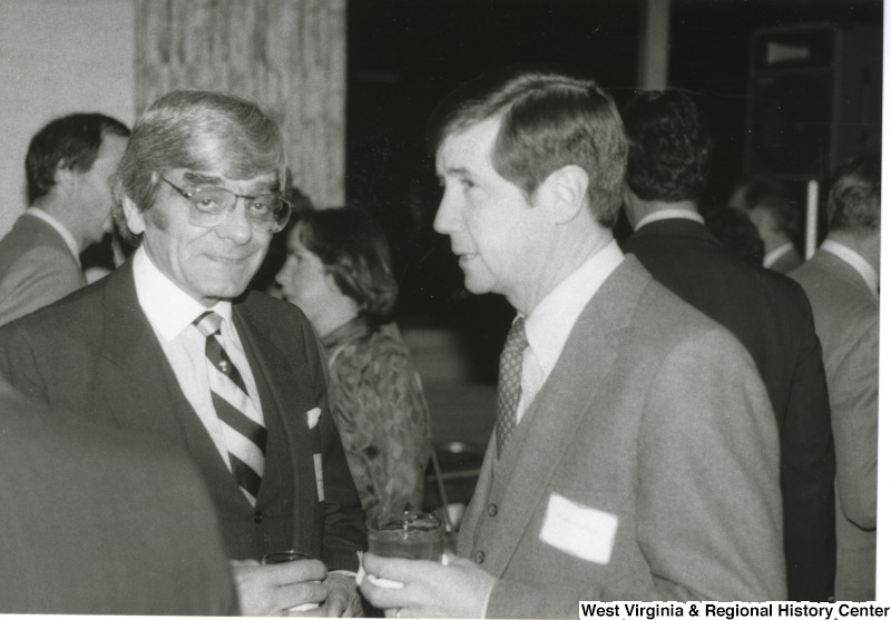 On the right, Mike Loftus speaks to an unidentified man at an event.