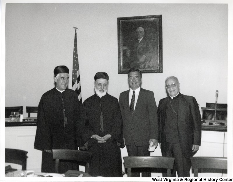 Second from the right, Representative Nick J. Rahall (D-W.Va.) stands for a photograph with three unidentified men, one of which is wearing a priest collar.
