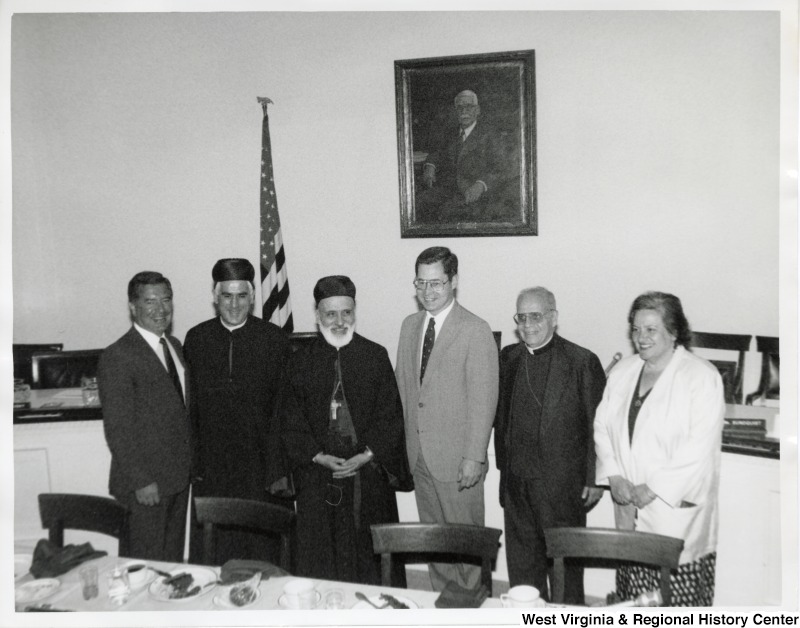 On the far left, Representative Nick J. Rahall (D-W.Va.) stands beside two unidentified men in religious garb standing next to Representative Harley O. Staggers (D-W.Va.). On the right of Representative Staggers is an unidentified man in a priest collar followed by an unidentified woman.