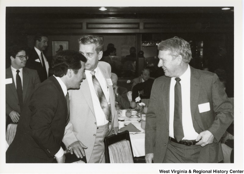 On the left, Representative Nick J. Rahall (D-W.Va.) talks with two unidentified men at an event.