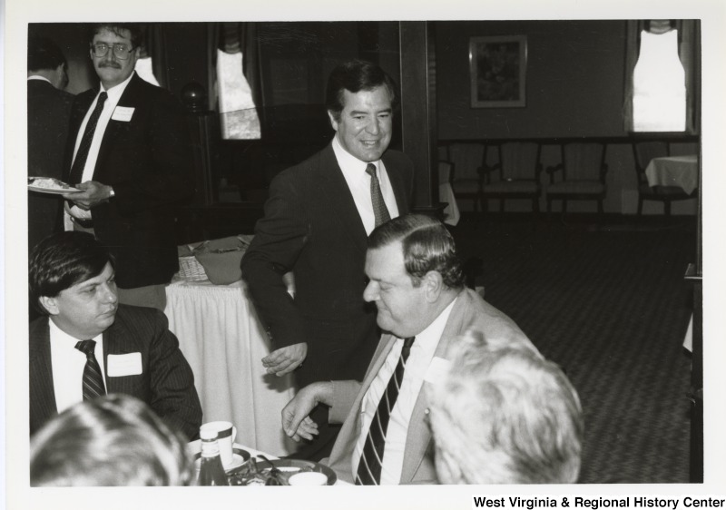 Representative Nick J. Rahall (D-W.Va.) stands near a group of unidentified men at an event.