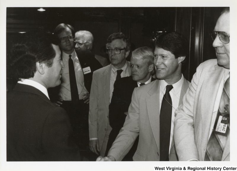 On the left, Representaive Nick J. Rahall (D-W.Va.) goes to shake hands with six unidentified men in a line at an event.