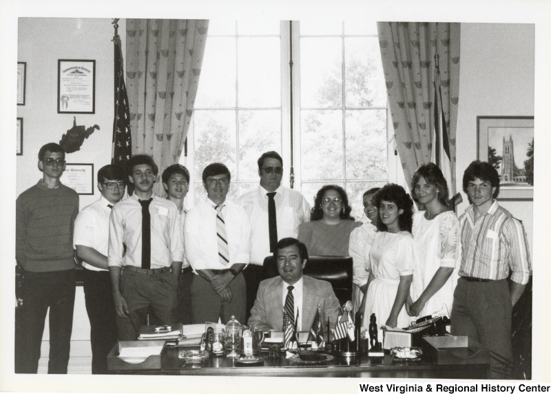 Representative Nick J. Rahall (D-W.Va) seated at his desk surrounded by students from the Mountain State Christian School and Principal Barry Holland.