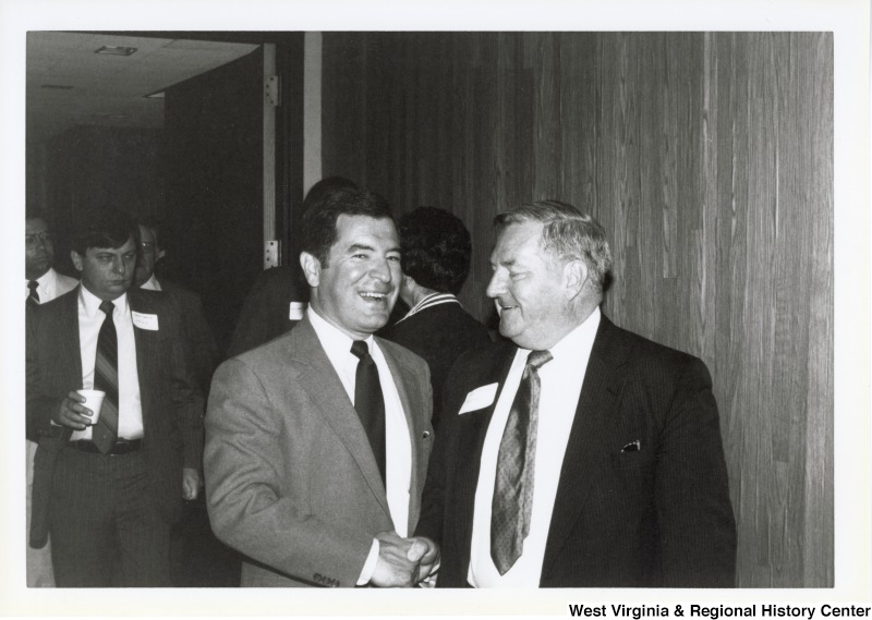 Representative Nick J. Rahall (D-W.Va.) shakes hands with an unidentified man at an event with a group of unidentified men.