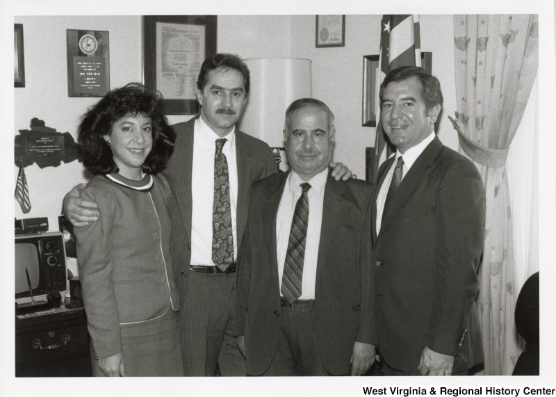 On the right, Representative Nick J. Rahall (D-W.Va.) poses for a photo with two unidentified men and an unidentified woman inside of an office.