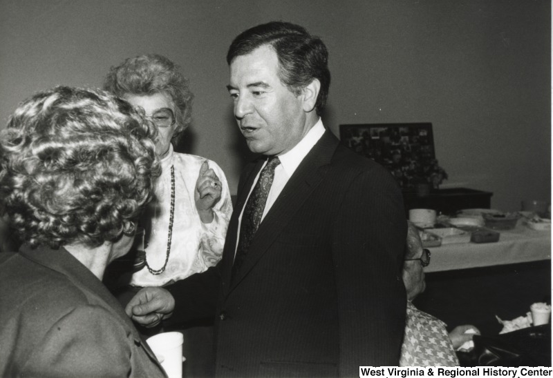 On the right, Representative Nick J. Rahall (D-W.Va.) talks with two unidentified older women.