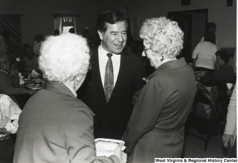 In the middle, Representative Nick J. Rahall (D-W.Va.) talks with two unidentified older women at an event.