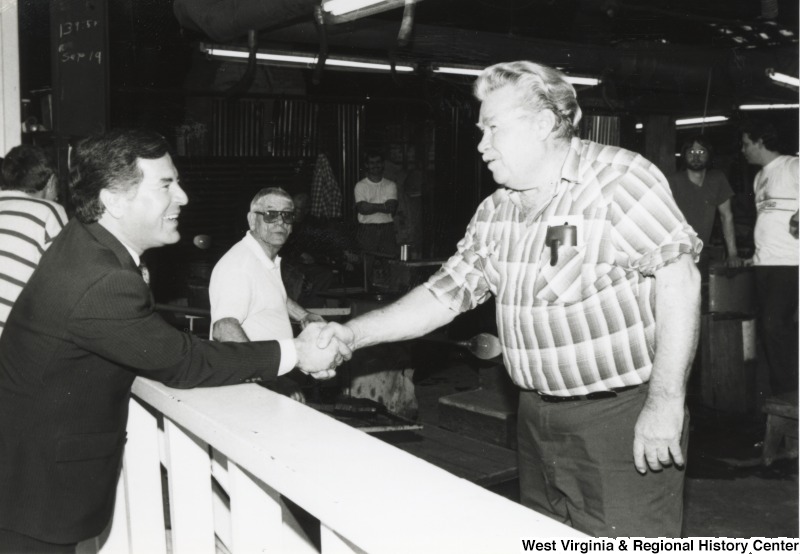 On the left, Representative Nick J. Rahall (D-W.Va.) shakes hands with an unidentified man.
