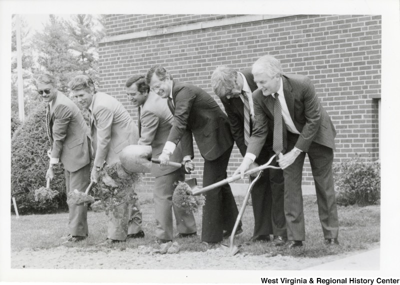 Third from the left, Representative Nick J. Rahall (D-W.Va.) lifts a shovel full of dirt for a groundbreaking, surrounded by five other unidentified men also breaking ground.