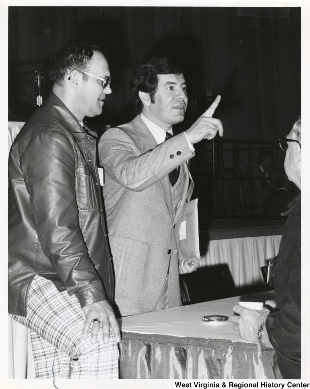 On the right, Representative Nick J. Rahall (D-W.Va.) stands and points while talking next to an unidentified man.