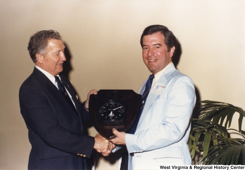 On the right, Representative Nick J. Rahall (D-W.Va.) shakes hands with an unidentified man and exchanges a clock.