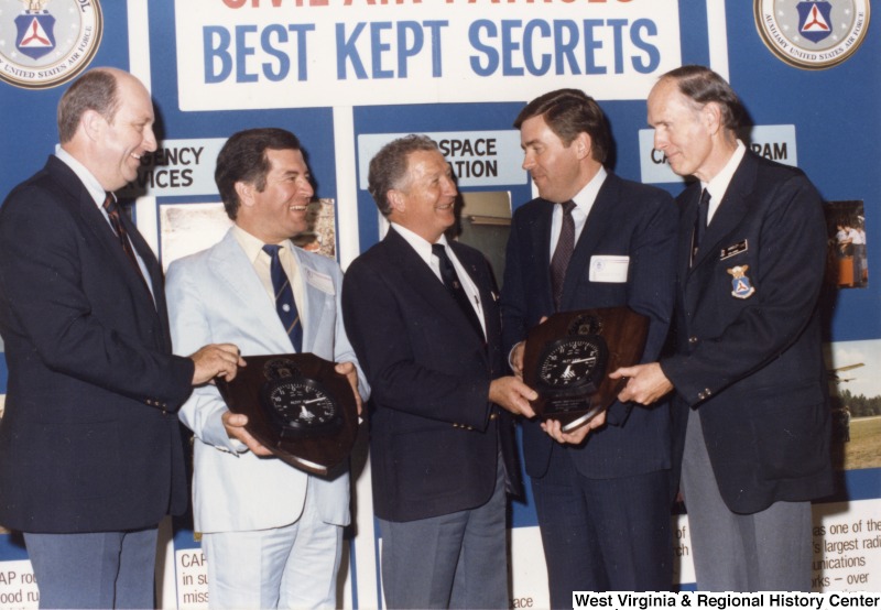 Second from the left, Congressman Nick J. Rahall (D-W.Va.) stands with four unidentified men of the Civil Air Patrol. Congressman Rahall is holding one of two clocks being presented.