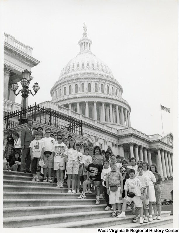 At the far left top of the stairs, Representative Nick J. Rahall (D-W.Va.) smiles for a picture with a group of school students outside the Capitol building.