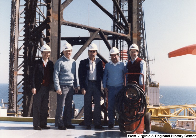 L-R: Representative Bob Matsui (D-Calif.), Representative Ronnie Flippo (D-Ala.), Representative Tony Coelho (D-Calif.), Representative Nick J. Rahall (D-W.Va.), Representative Alan Mollohan (D-W.Va.). The Congressmen all wear Mobil Oil hard hats and stand in front of machinery while visiting an oil rig in the Gulf of Mexico.