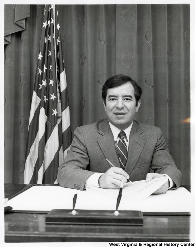 Representative Nick J. Rahall (D-W.Va.) sits behind a desk ready to sign papers.