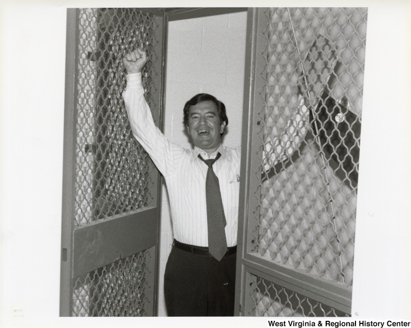 Representative Nick J. Rahall (D-W.Va.) is pictured with his hands in the air inside a building.