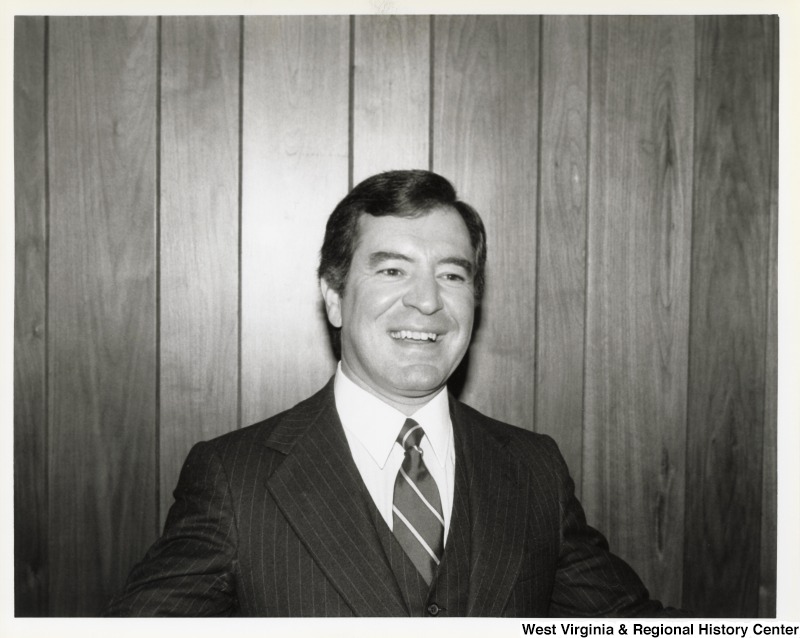 Representative Nick J. Rahall (D-W.Va.) is pictured in front of a wood background.