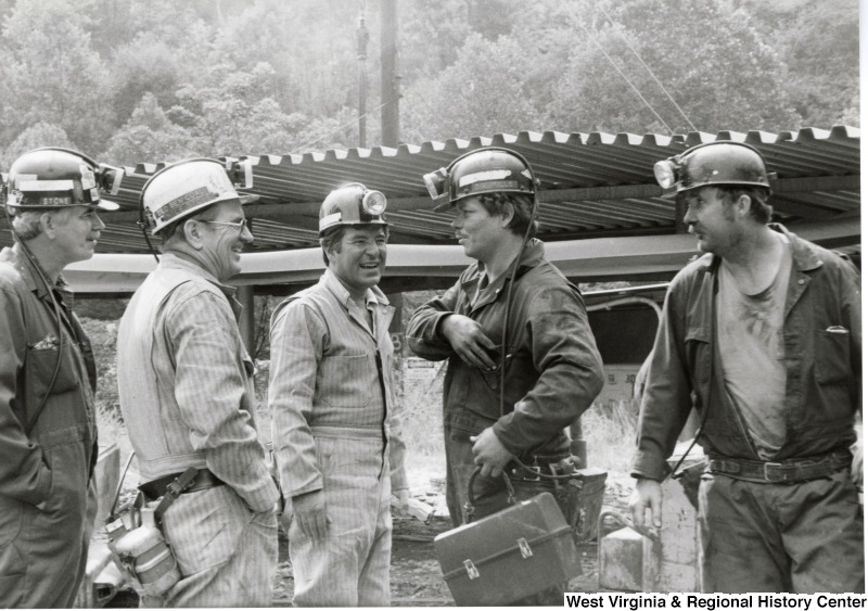 Congressman Nick Rahall dressed in coal miner uniform at Old Ben Coal Mine with three unidentified coal miners and Ben Stone, Secretary-Treasurer of United Mine Workers of America (UMWA).From left to right: Ben Stone, unidentified miner, Congressman Nick Rahall, and two unidentified miners.