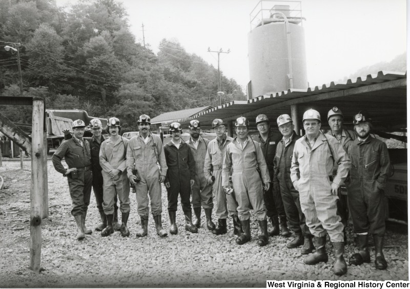 Congressman Nick Rahall dressed in a coal miner uniform outside of Old Ben Coal Mine with a group of unidentified coal miners.
