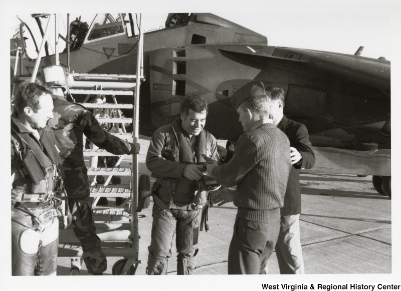 Congressman Nick Rahall receiving instructions from two United States Marine Corps service members in front of the Harrier Jet in Qauntico, Virginia.