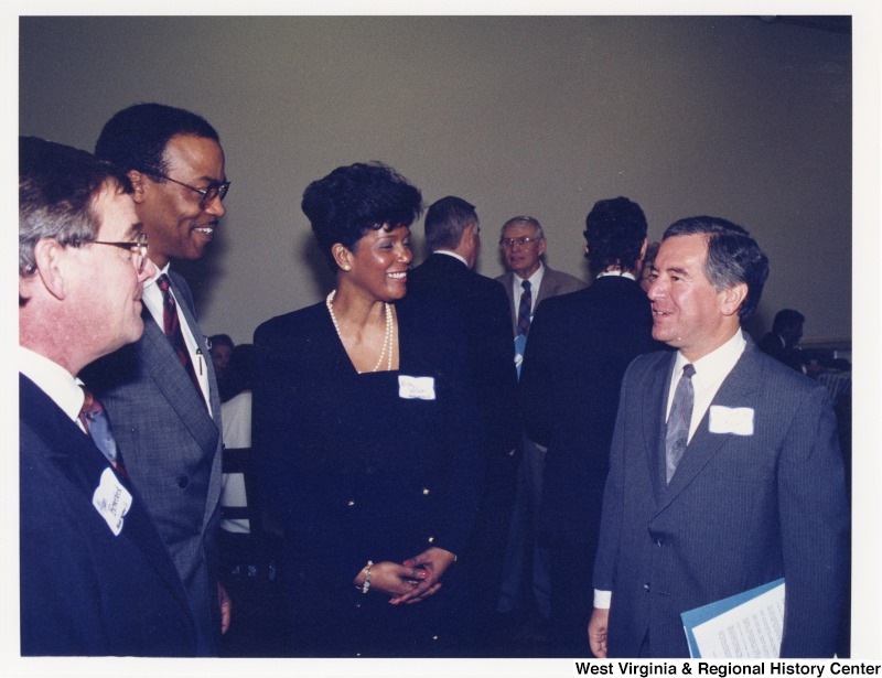 Congressman Nick Rahall (D-WV) speaking with three unidentified people at a social gathering.