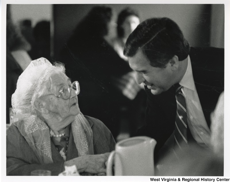 Congressman Nick Rahall (D-WV) speaking with an unidentified senior woman at a dinner table.