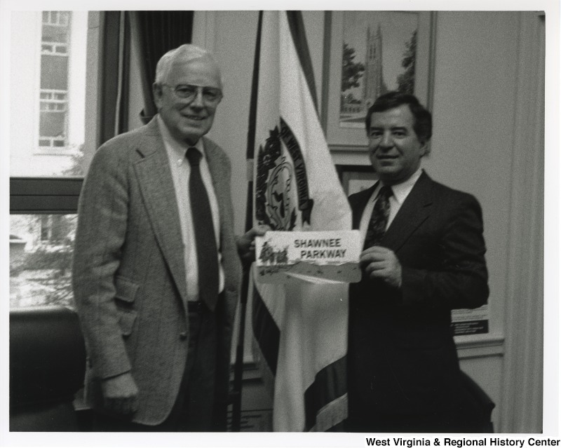 Congressman Nick Rahall (D-WV) with an unidentified man holding a "Shawnee Parkway" sign at his office.