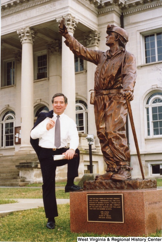 Representative Nick J. Rahall (D-W.Va.) stands with one foot up on a monument to Boone County, WV coal miners after the Boone County Bean Dinner.