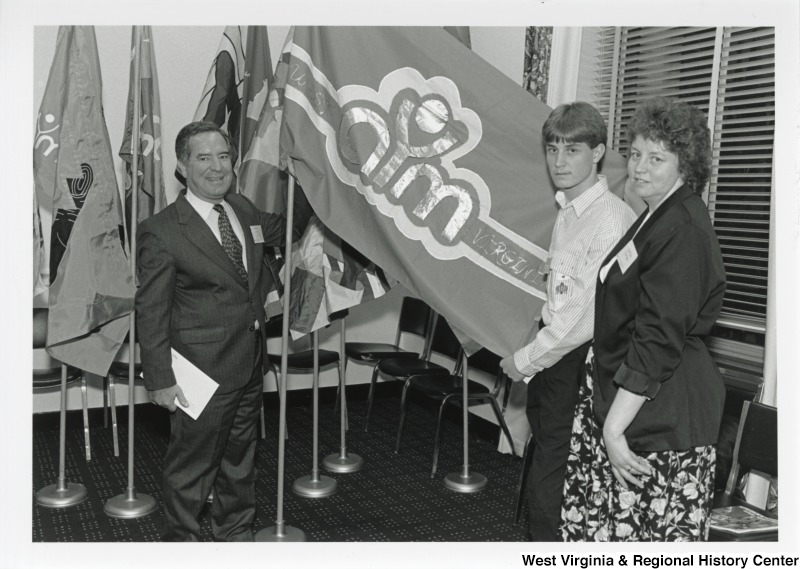 On the left, Representative Nick J. Rahall (D-W.Va.) is seen holding a school flag with Jeffery and Clara Deyton for National Youth Art Month.