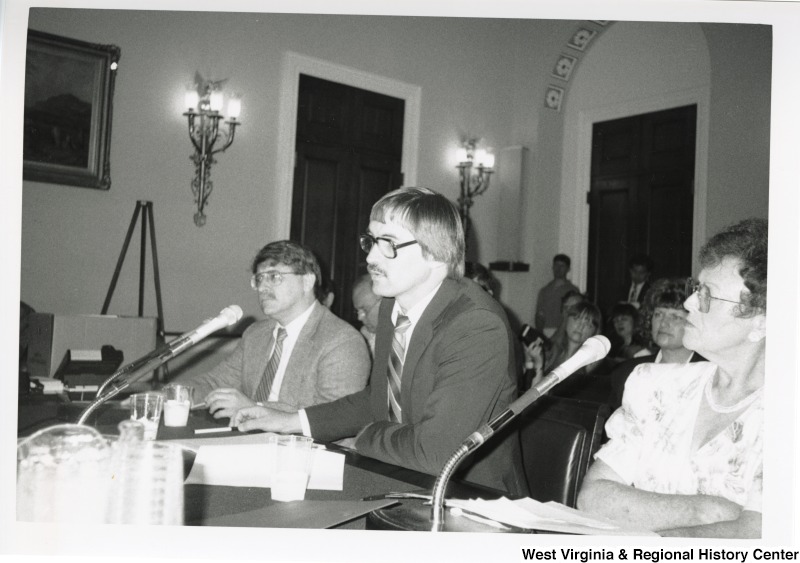 L-R: Mr. Zacher, Jim McNeel, Ms. ComptonThese three sit at a panel behind microphones in front of a crowd at the New River hearing.